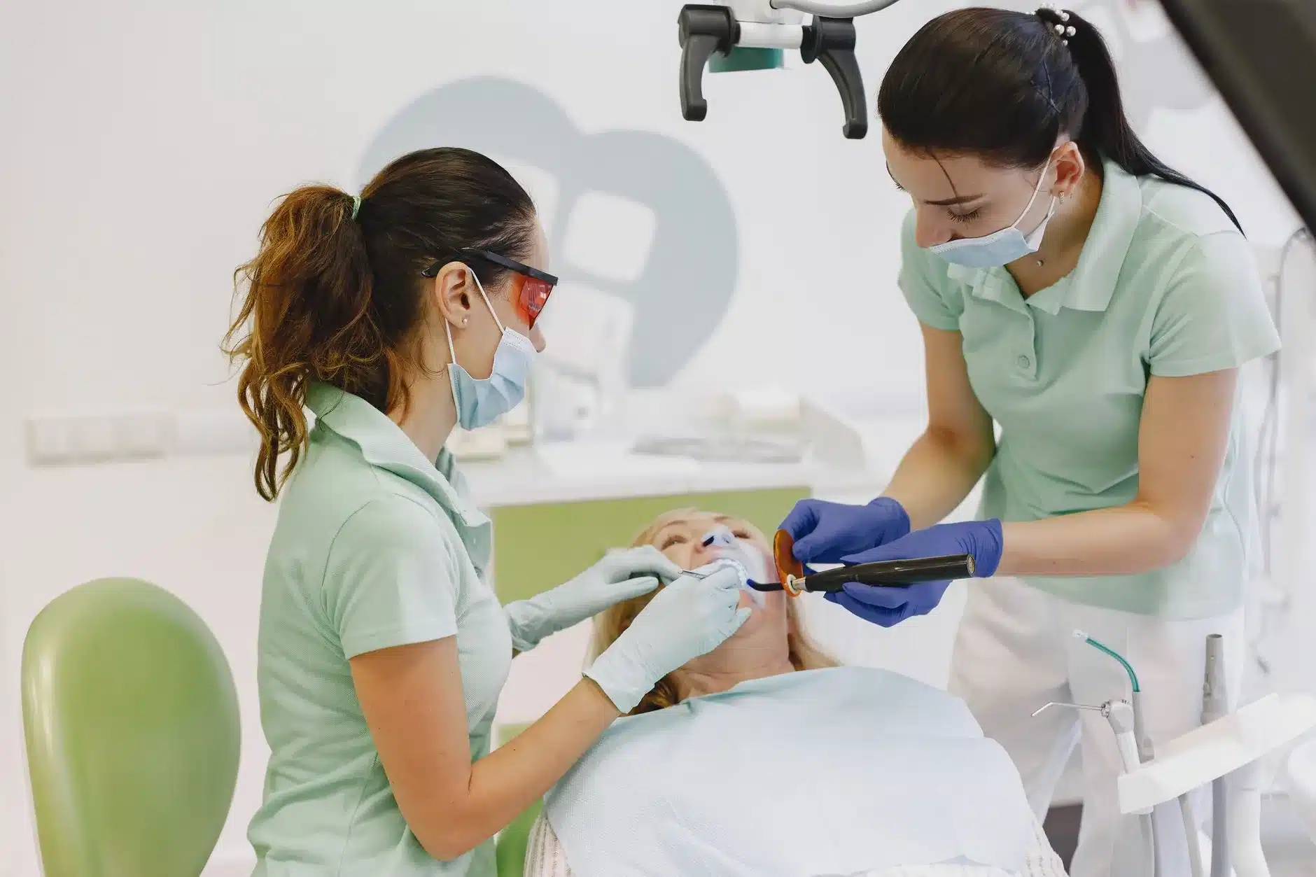 Deux dentistes réalisent un soin dentaire sur une patiente en cabinet