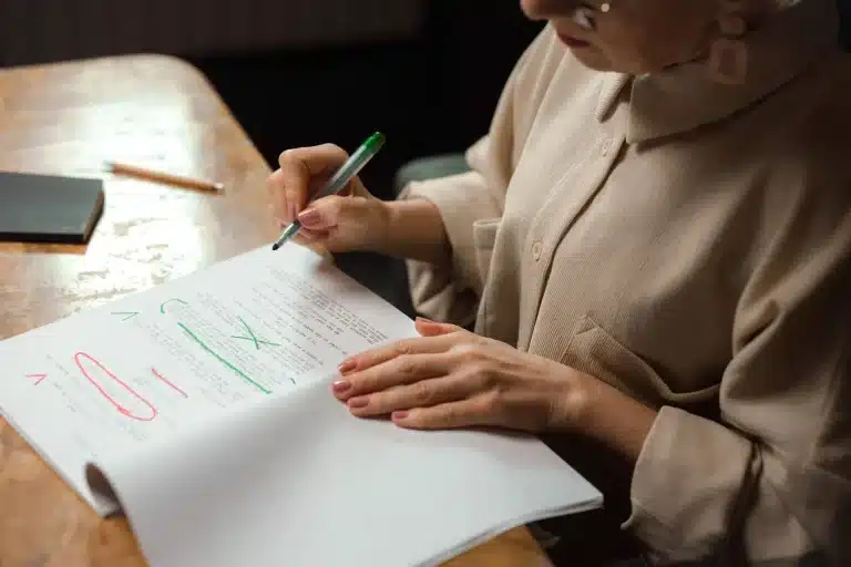 Femme annotant un document avec un marqueur vert, surlignages colorés visibles